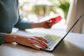 A woman uses a laptop as she holds a debit card