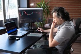 Man sitting at a desk looking intently at a laptop.