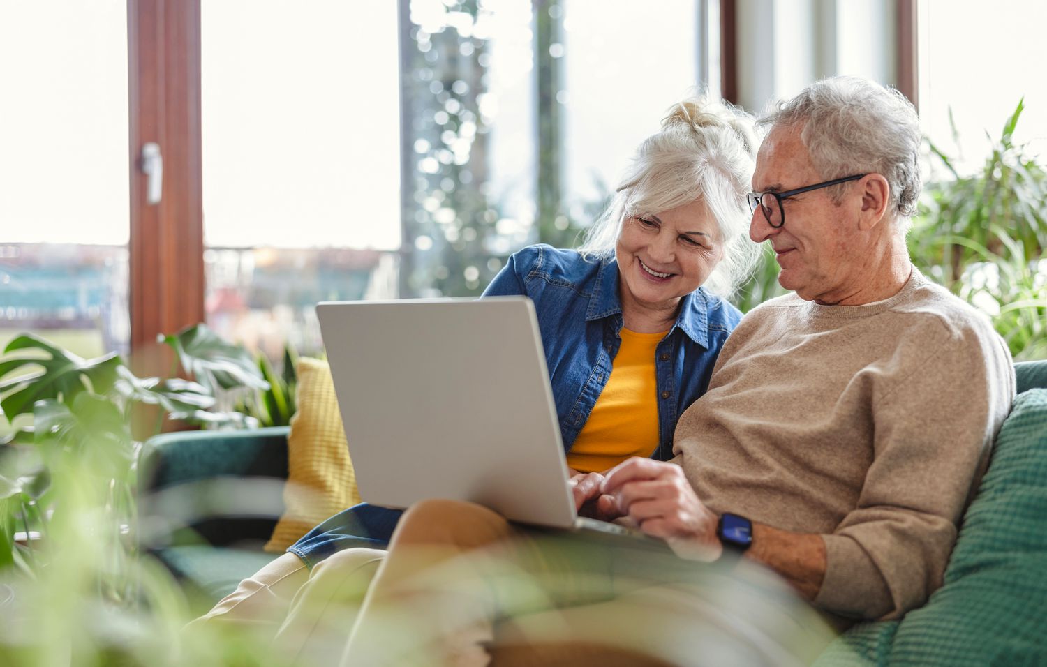 Older couple smiling at computer while sitting on a couch