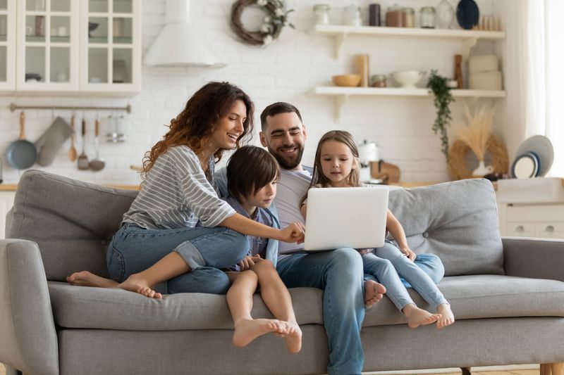 Happy young family sitting on a couch looking at a laptop
