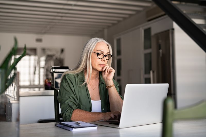 A woman is thinking at the computer.