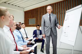 Professor teaching young managers by whiteboard.