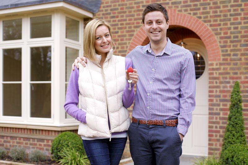 Couple holding keys to their house in front of their house