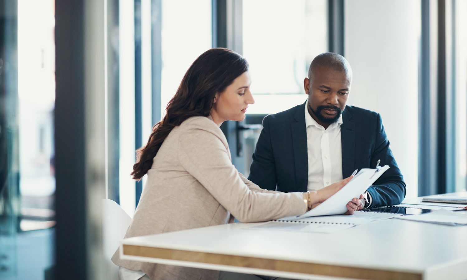 A business owner and a banker sit at an office desk and discuss using investment securities as collateral for a loan.
