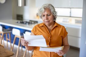 Senior Latin American woman at home reading a letter she got in the mail.