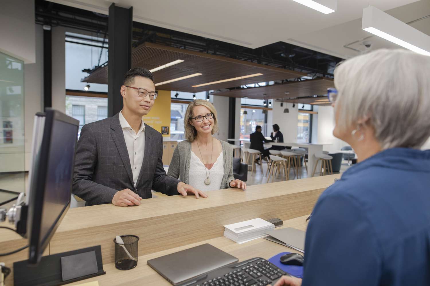 Bank teller at computer helping couple at bank branch counter