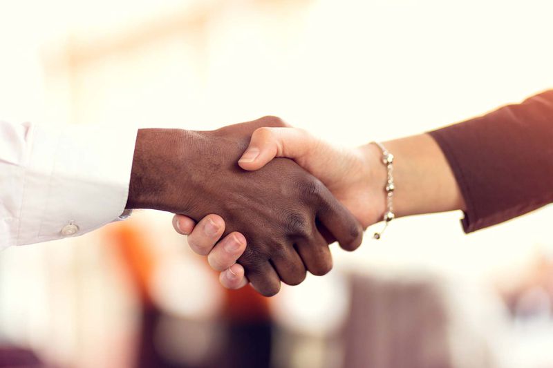 Closeup of White and Black shaking hands over a deal