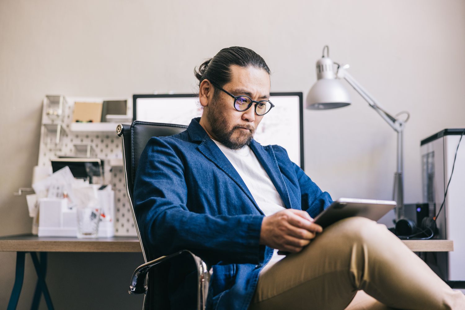 Designer in his workspace, focusing on a digital tablet in his hands.