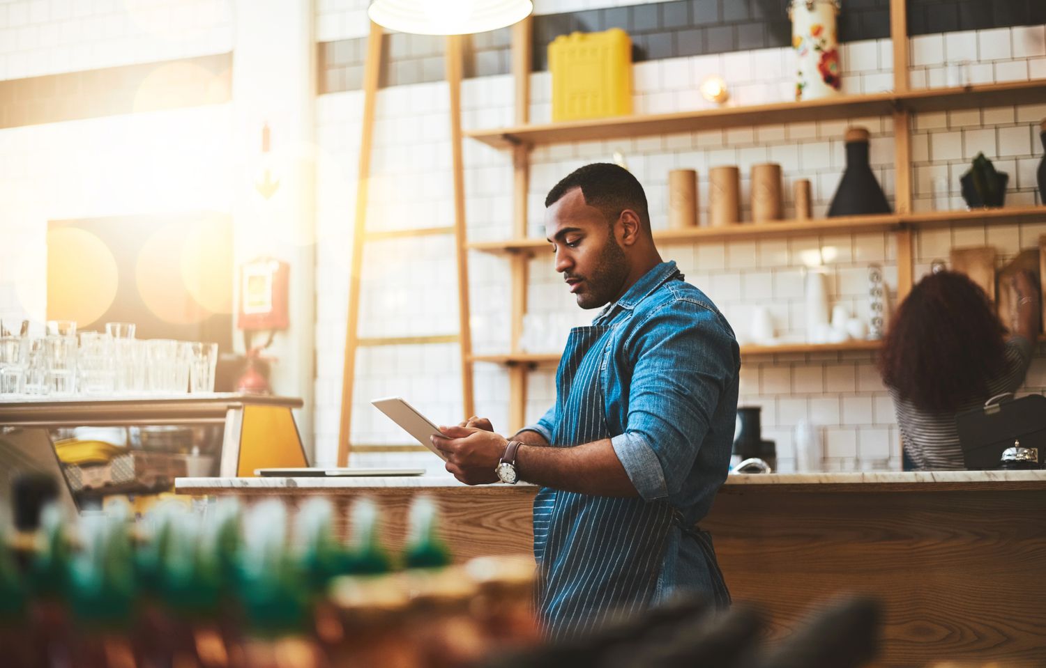 Young man working on a tablet in his coffee shop.