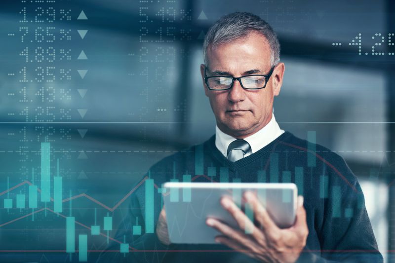 A business person uses a computer pad to search for available derivative contracts to hedge the company's currency exchange rate risk.