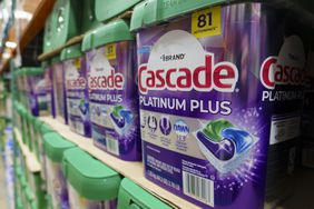 Packages of Cascade dishwasher detergent pods are stacked on on top of each other inside a Costco store.