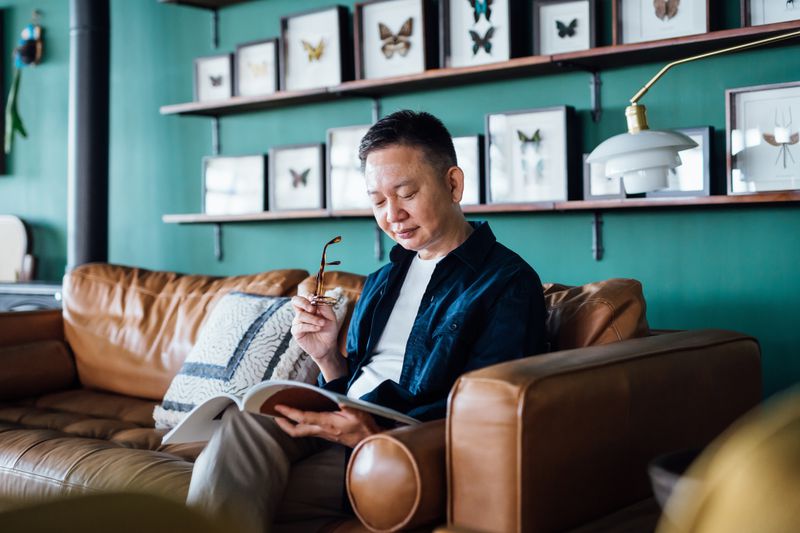 A man sits on a couch and reads a book