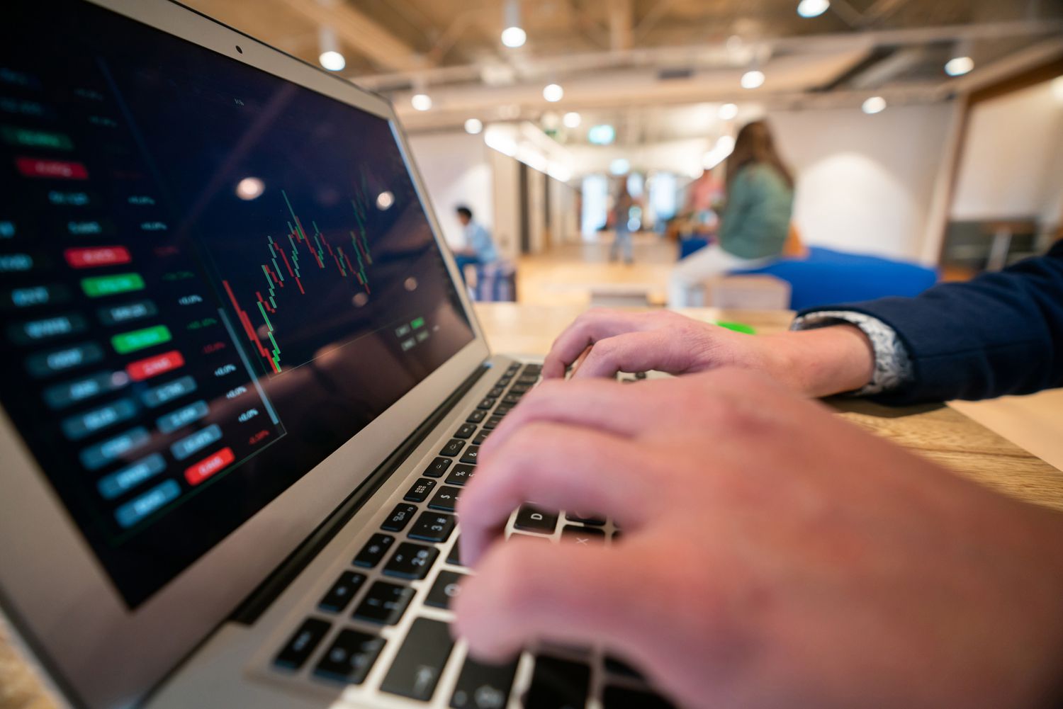 An investor uses a laptop in a workplace lounge area to track the price changes on a stock they are researching.