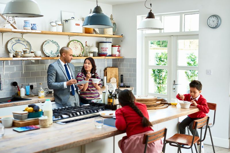 Busy family with two children sitting at the kitchen counter, discussing getting their home equity back after paying off their loan.