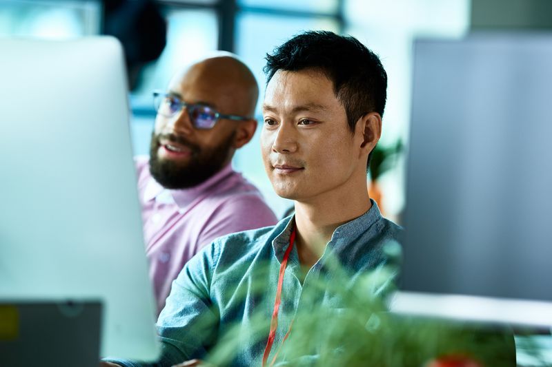 Chinese office worker at desktop computer with colleague