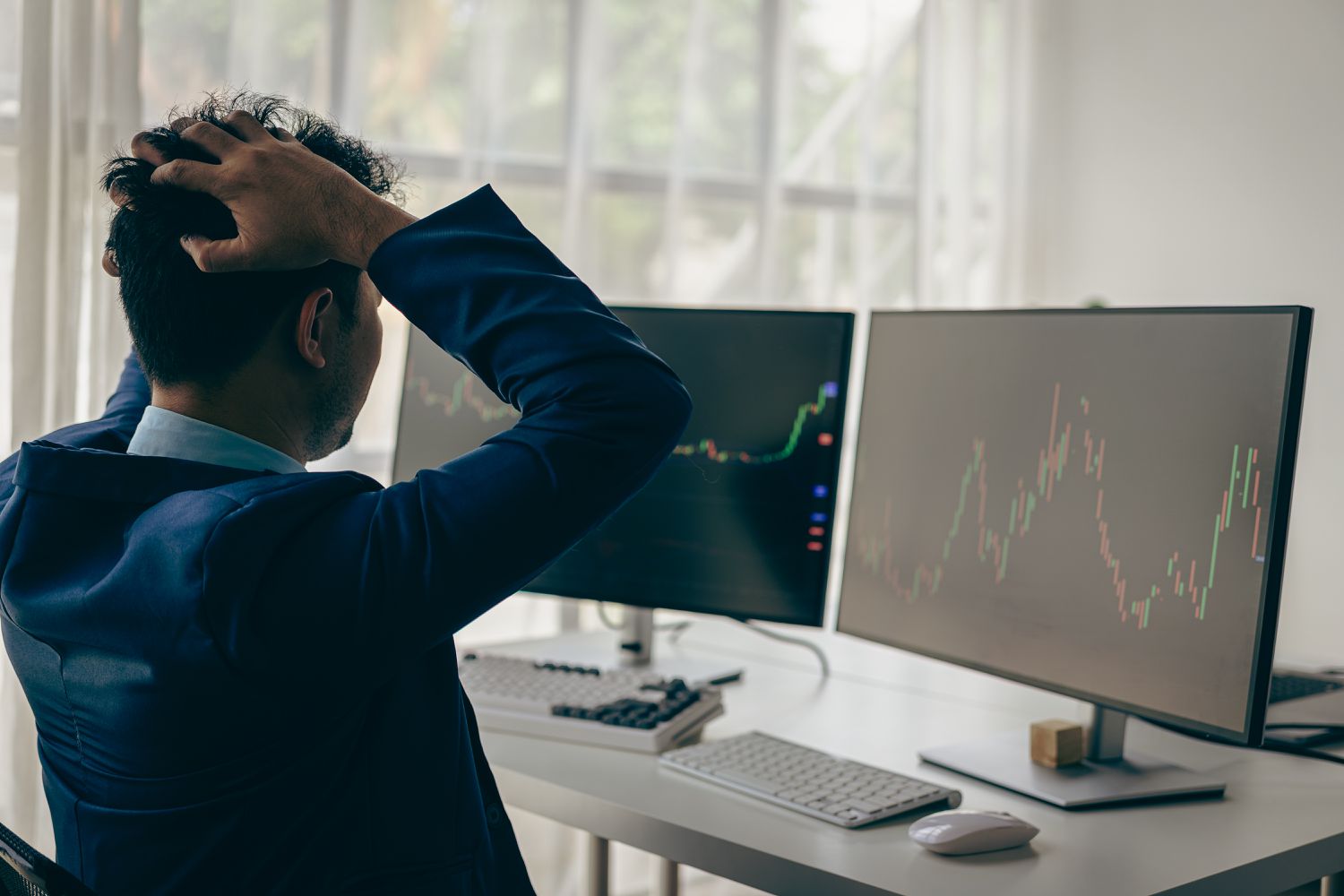 An investor holds their head in surprise and despair after seeing a stop-loss order trigger during wild stock market swings.