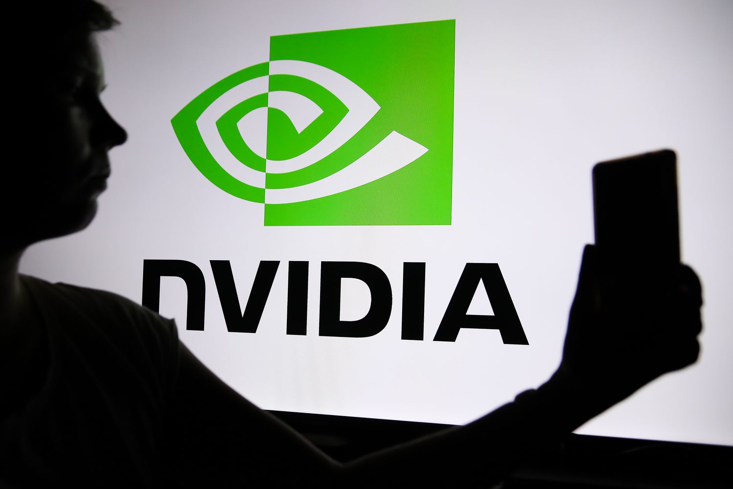 The Nvidia logo with a person holding a phone in their hand