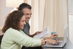 Couple sitting beside each other pay taxes using a laptop