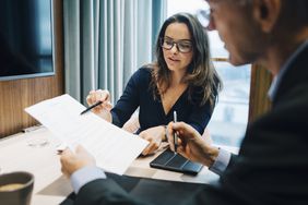 Two business executives review documents.