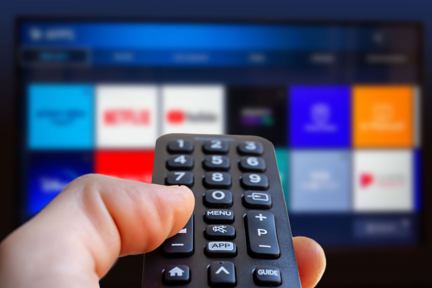 A person is holding a remote control of a smart TV in his hand.