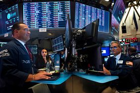 Two traders face computer screens while working at desks at the New York Stock Exchange.