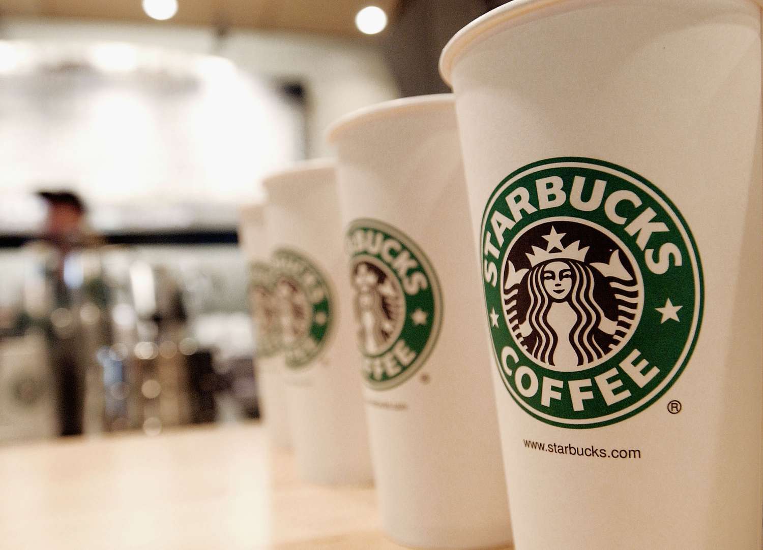 Line of paper cups featuring the logo of Starbucks Coffee.