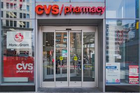 The entrance to a CVS Pharmacy is seen with logos and ads in the windows.