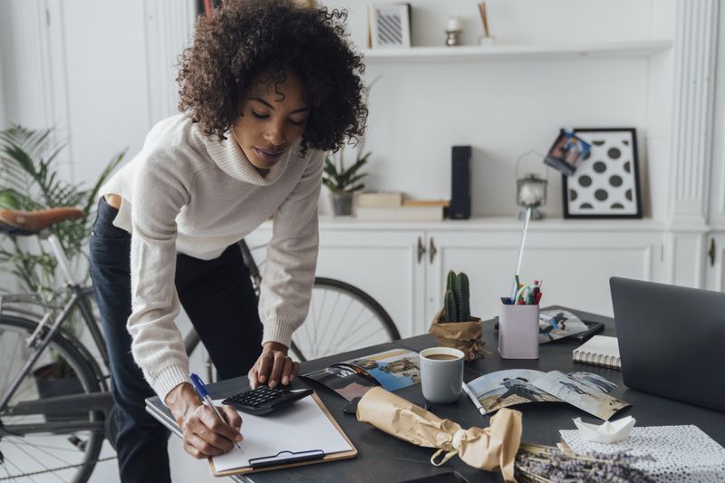 A woman makes calculations at a desk.