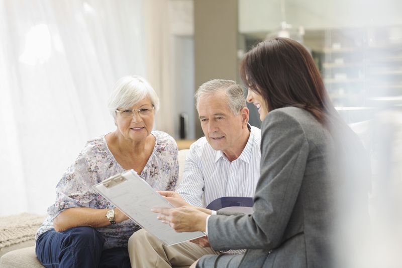 Financial advisor talks to an older couple on sofa.