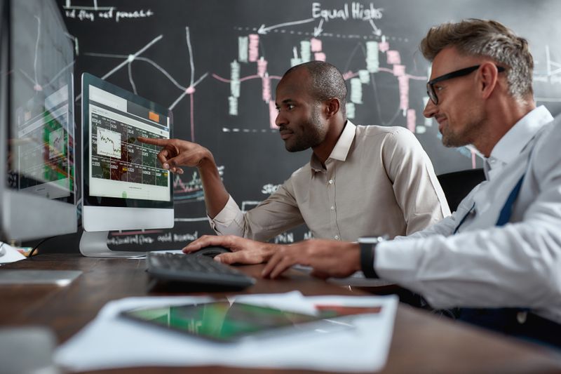 Stock traders looking at different indexes shown on the computer screen to decide which market to invest in.