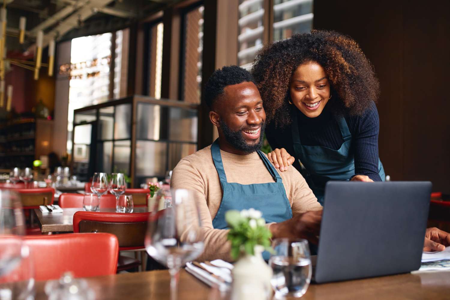 Small business owners inside their restaurant smiling happily since their loan's interest drops to a lower rate because of central bank's zero-bound strategy.
