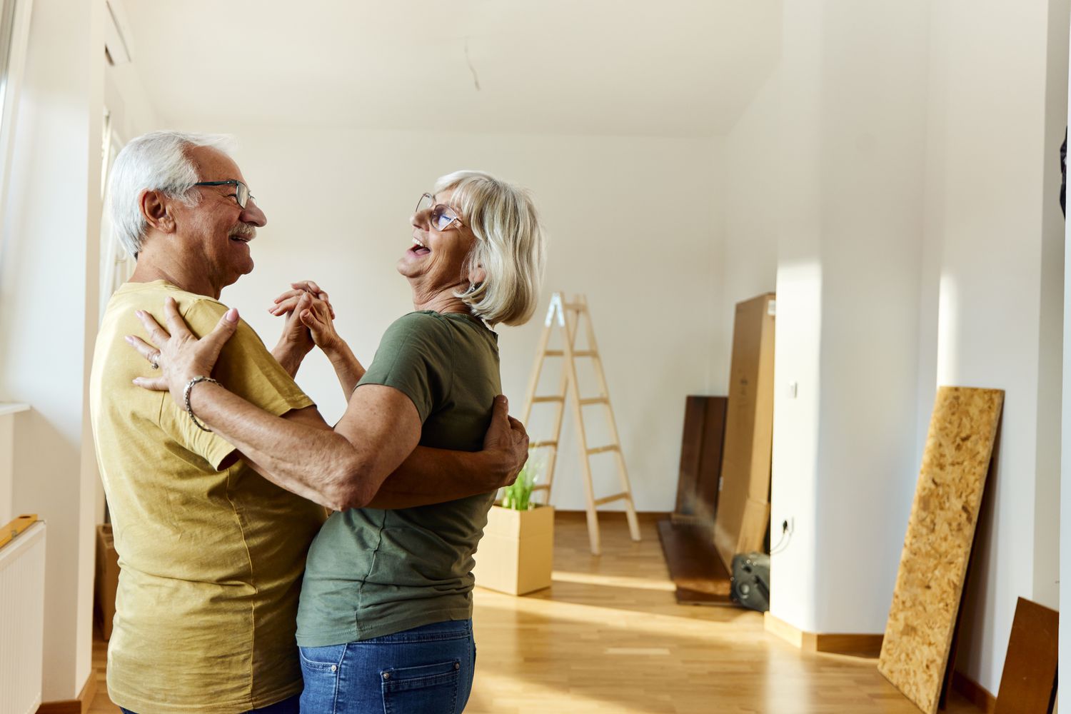 Senior couple dancing happily in their new home after changing their Medicare coverage successfully through special enrollment period due to moving.