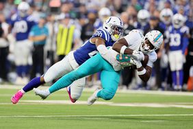 A Miami Dolphins football player is tackled by a player for the Indianapolis Colts.