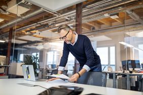 Businessman standing in office reading a document.