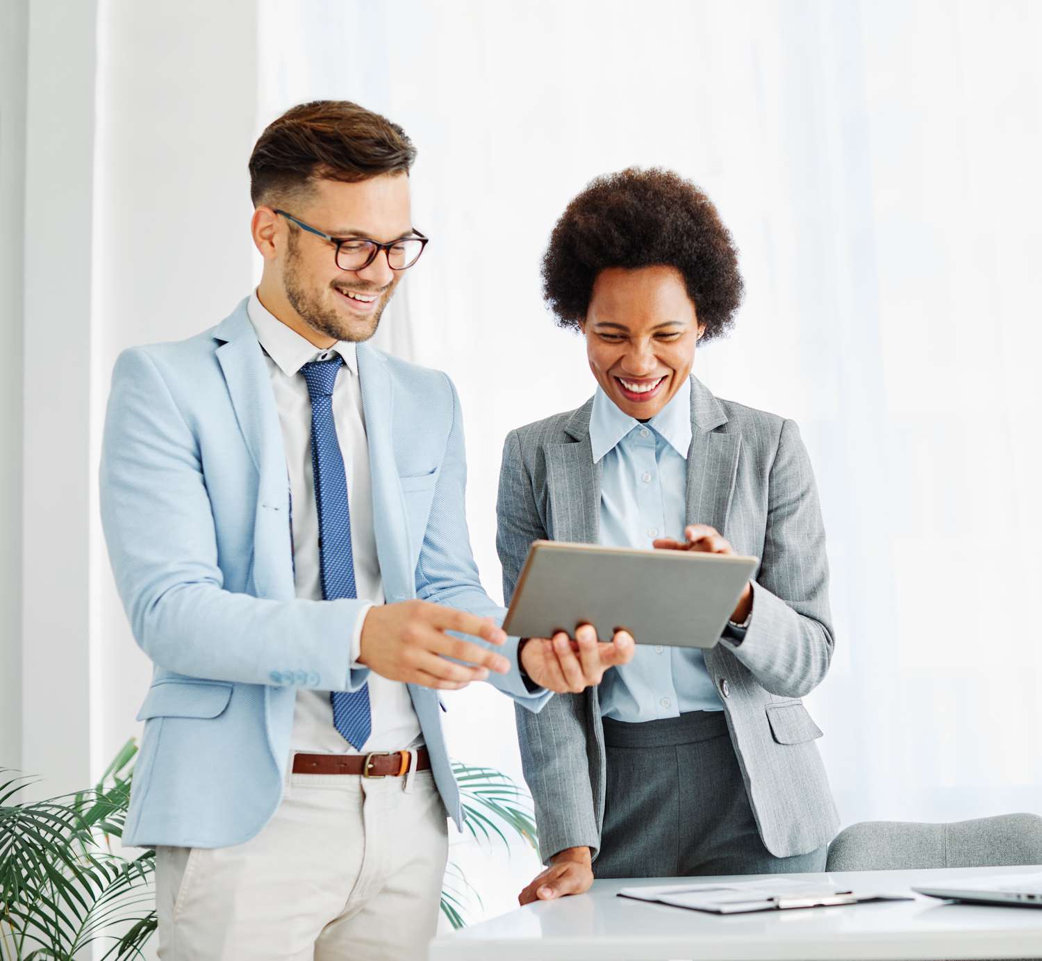 Two people in suits looking at a tablet