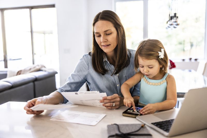 Mother looking through paperwork while young child is sitting on her lap.