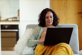 A mature woman is working from home a on laptop while sitting in her living room.