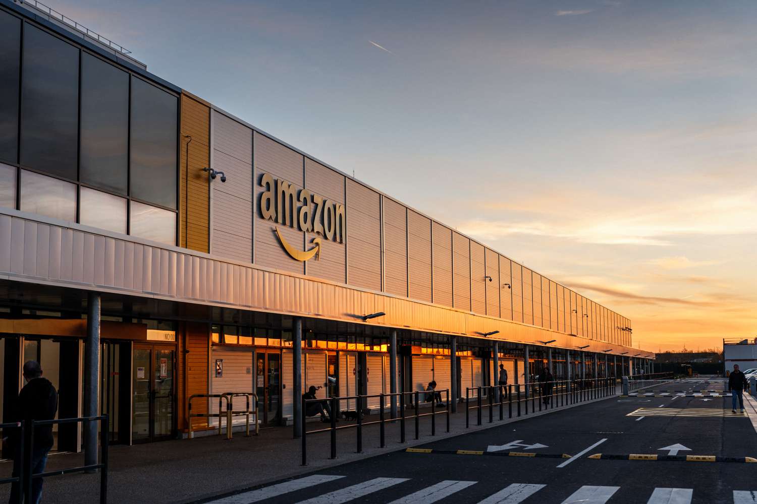The Amazon logo appears on the facade of one of the company's buildings in France at sunset.