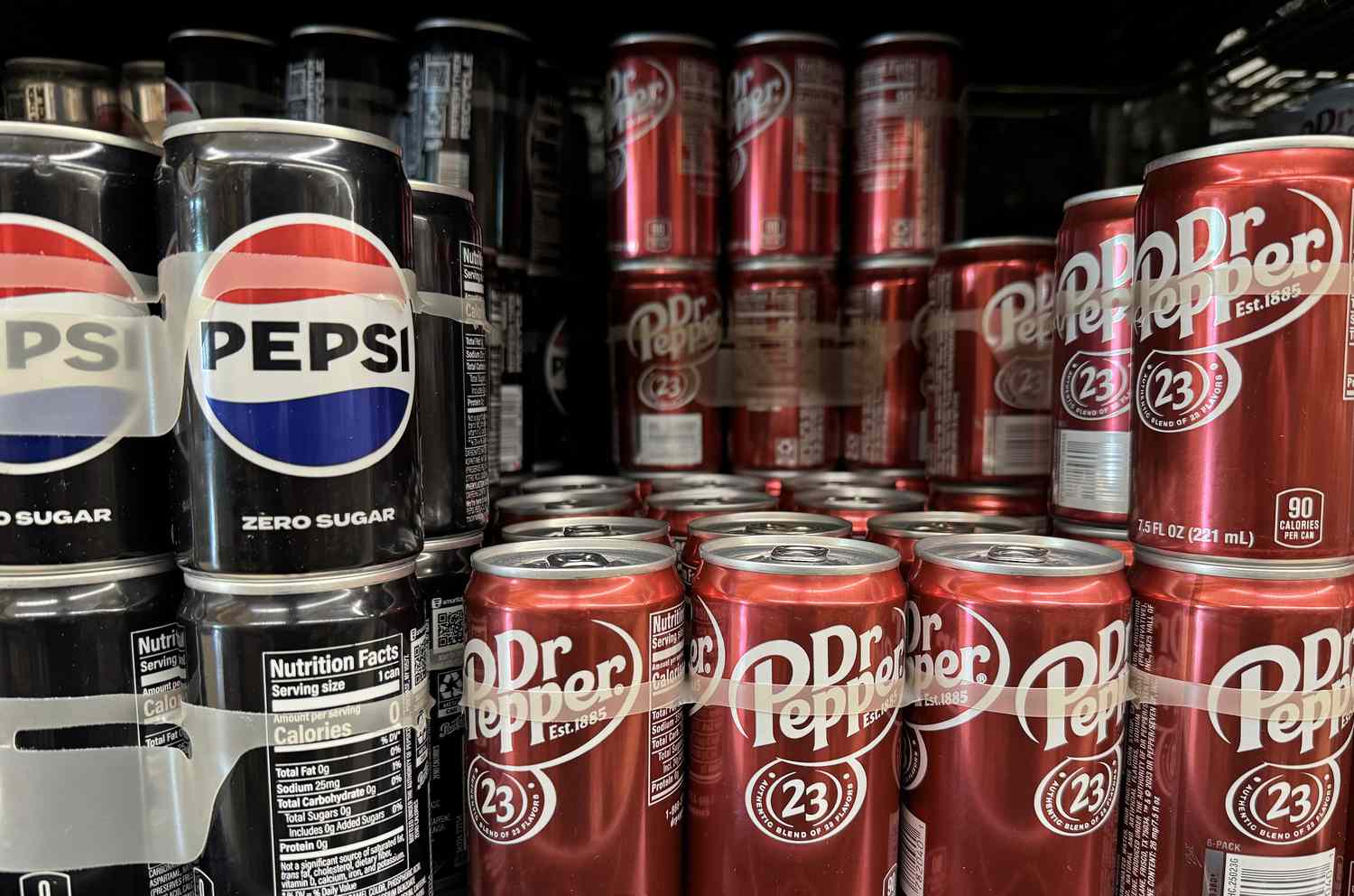 Cans of Zero Sugar Pepsi and Dr. Pepper are seen on a shelf.