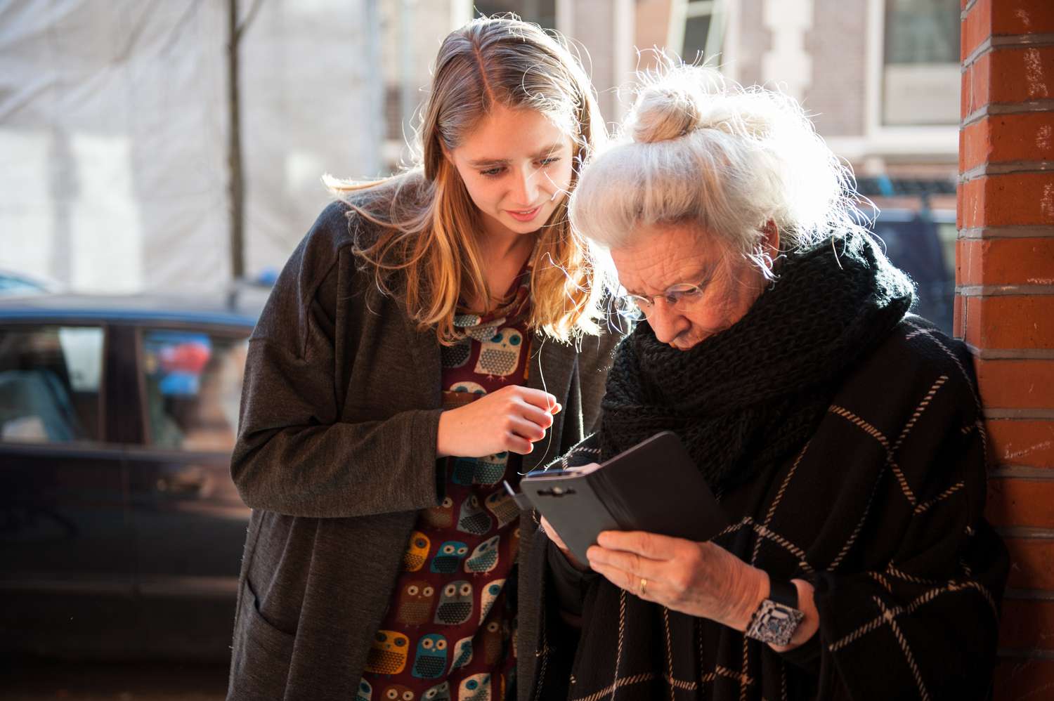 older woman looks at mobile phone while younger person with her looks on