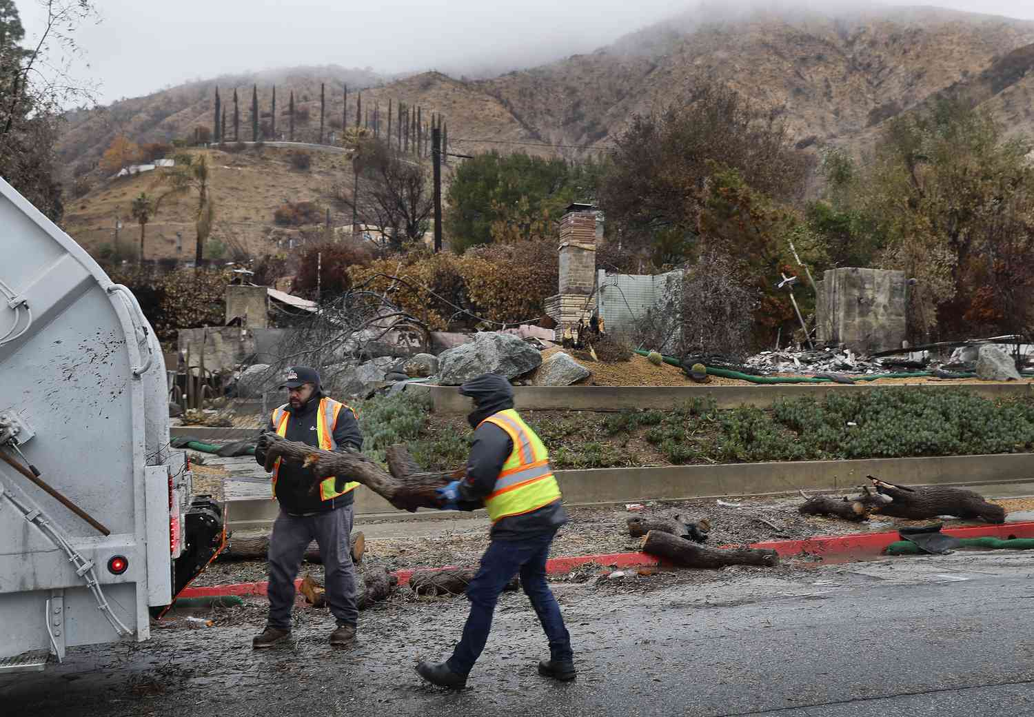 Crews remove downed trees blocking the gutter as they prepare for flooding and debris flow in the rain in the Eaton fire burn zone in Altadena Thursday, Feb. 13, 2025