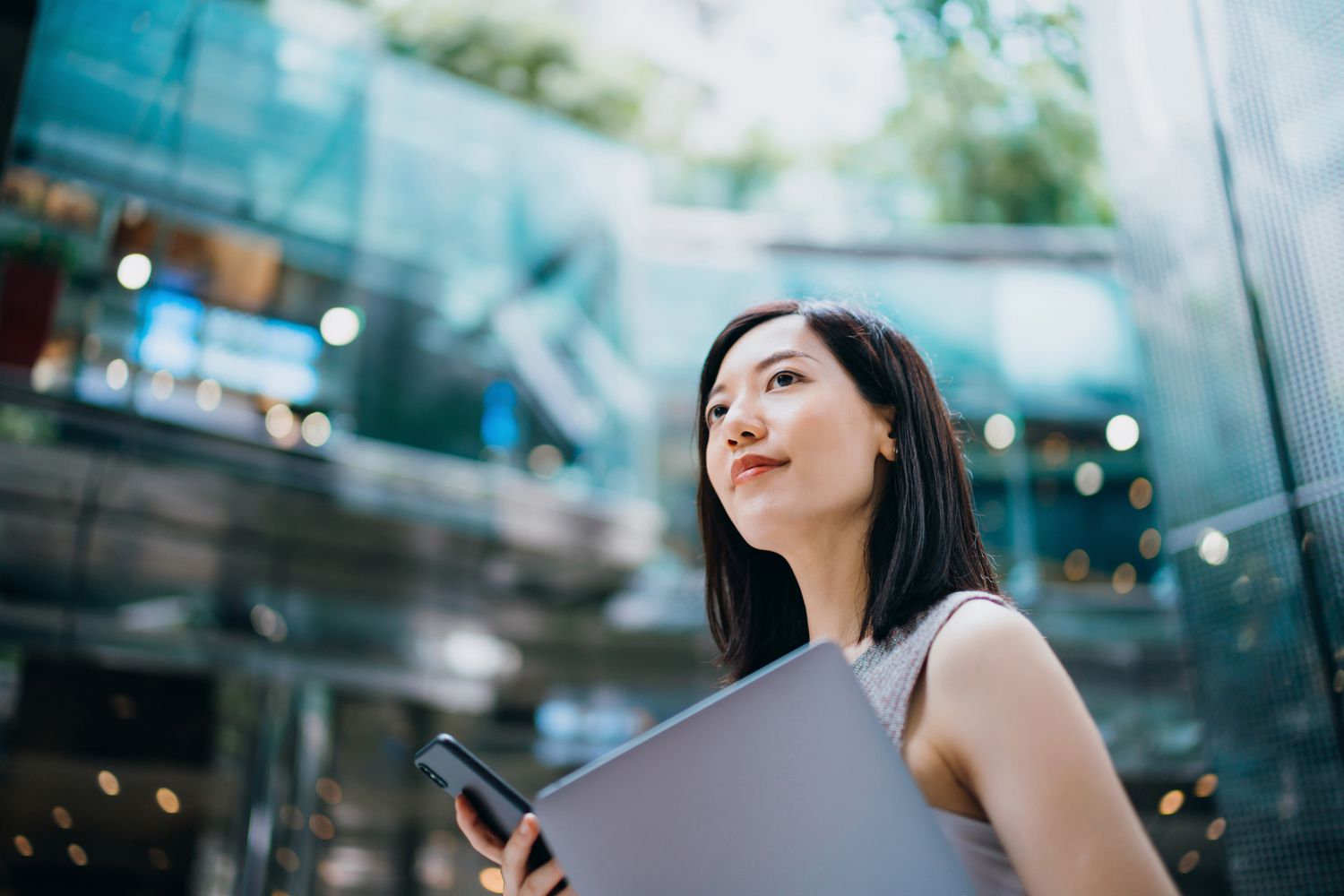 Young, successful businesswoman carrying a smartphone and a laptop. 