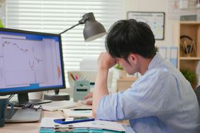 Worried investor looking at charts on a monitor.