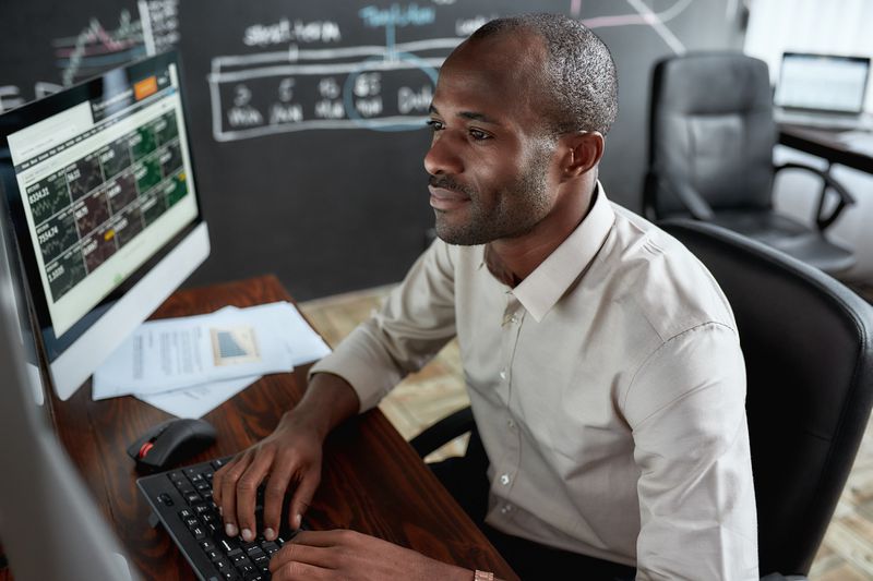 A stock trader reviews financial data on several computer monitors.