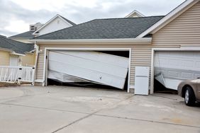 Damaged garage doors on a residential building, siding shows no additional damage
