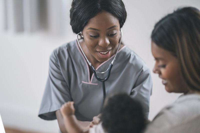 A mother holds her newborn baby at a routine medical checkup.