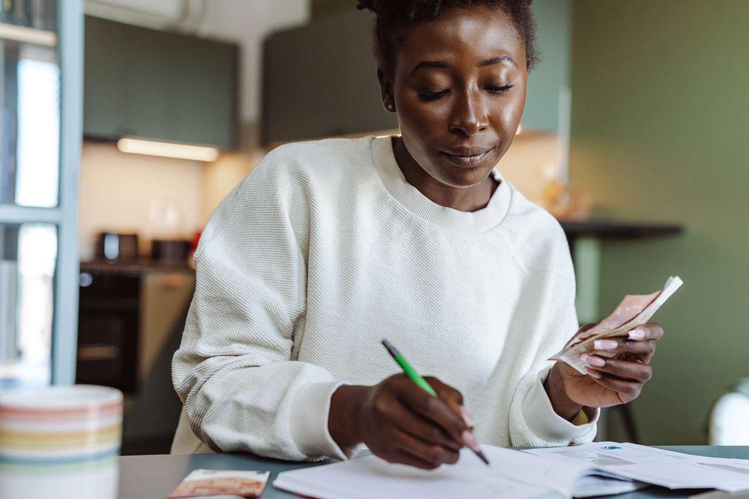 A woman holding cash and doing a budget