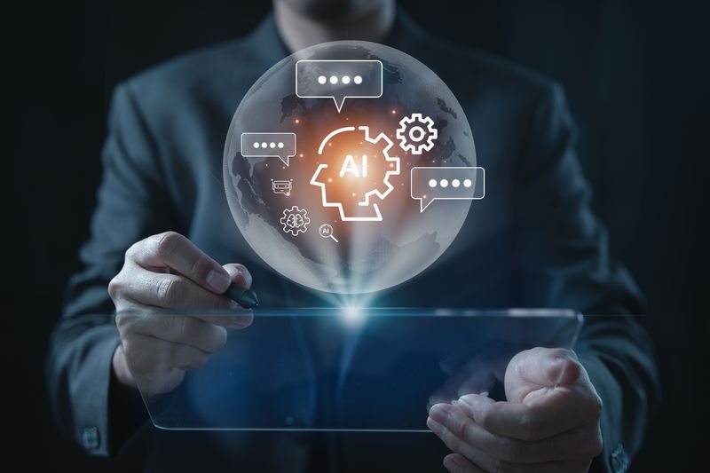 A person is at a table and hovering over it is a symbol of AI in the middle of a globe.