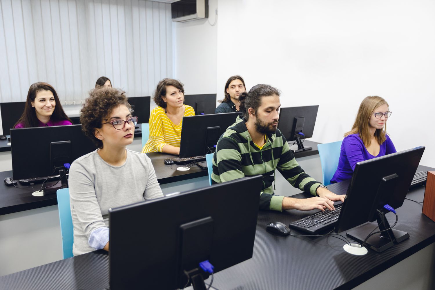 A classroom of college students work on computers as they learn how to use a trading system.