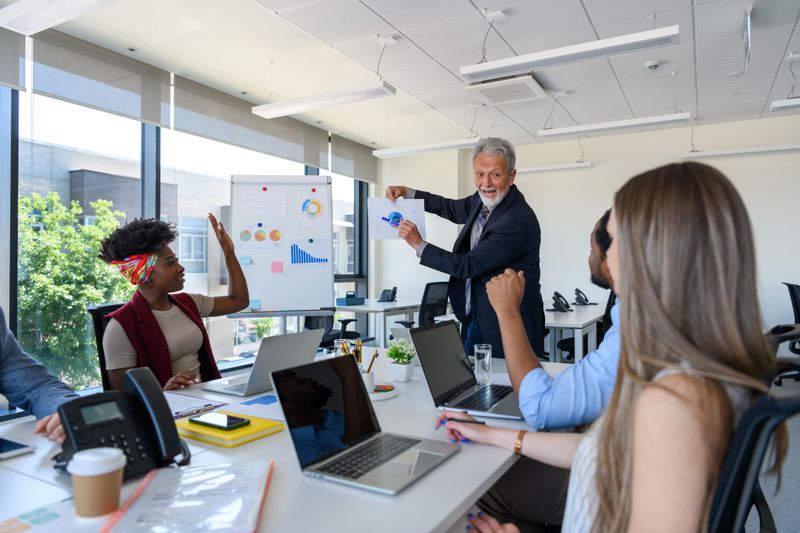People sitting at a conference table listing to a man presenting